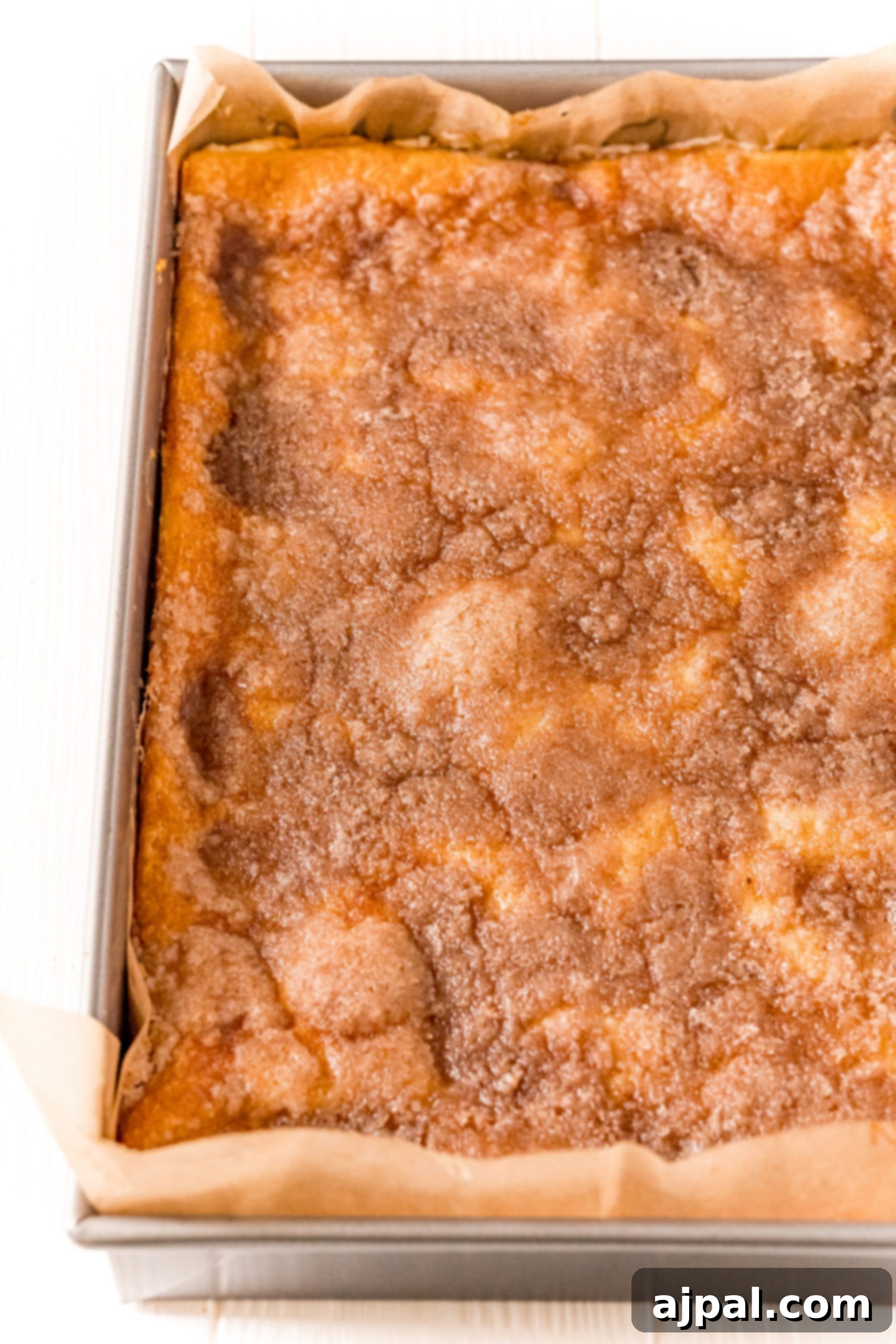 The baked apple sopapilla cheesecake bars in the pan, golden brown and puffed up.
