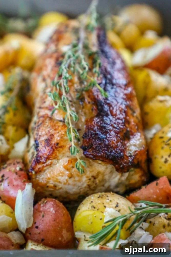 Succulent pork loin with rosemary sprigs and roasted potatoes, perfectly cooked and seasoned.