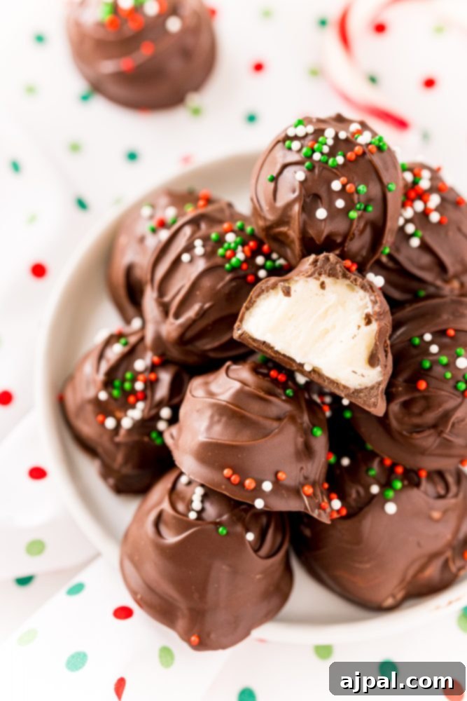 A pile of chocolate-covered peppermint buttercream candies with green, white, and red sprinkles, artfully arranged on a pristine white plate.