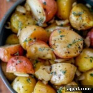Picture of garlic butter roasted potatoes in a blue bowl with herbs on top.
