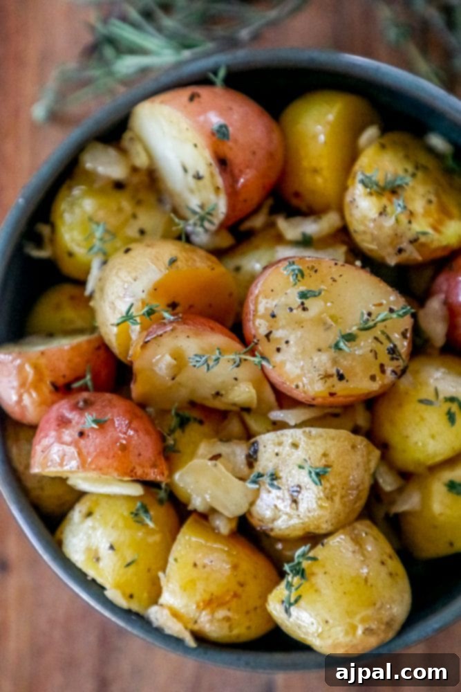 Delicious roasted Yukon Gold potatoes with fresh sprigs of thyme, served in a ceramic bowl.