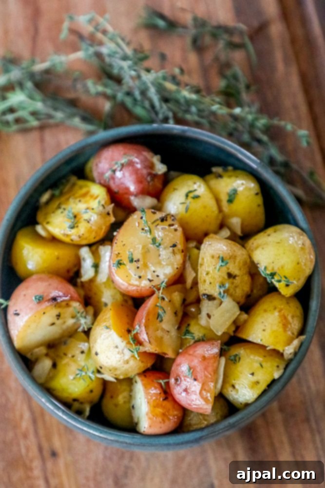 Roasted potatoes with thyme in a garlic butter bowl, ready to be served.