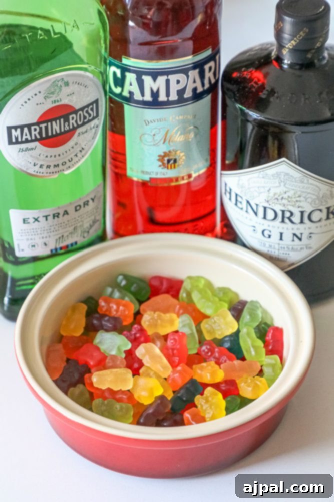 A bowl of vibrant Negroni gummy bears, with bottles of gin, vermouth, and Campari blurred in the background, hinting at their inspiration.