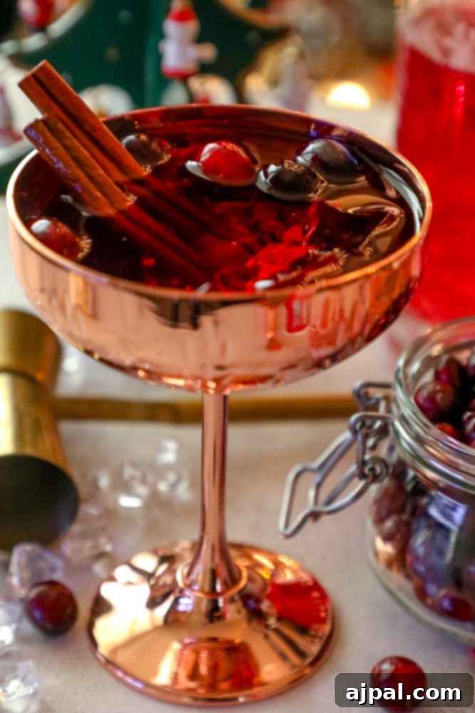 A flavorful Christmas sangria recipe featuring cranberries and cinnamon served in a copper cup.