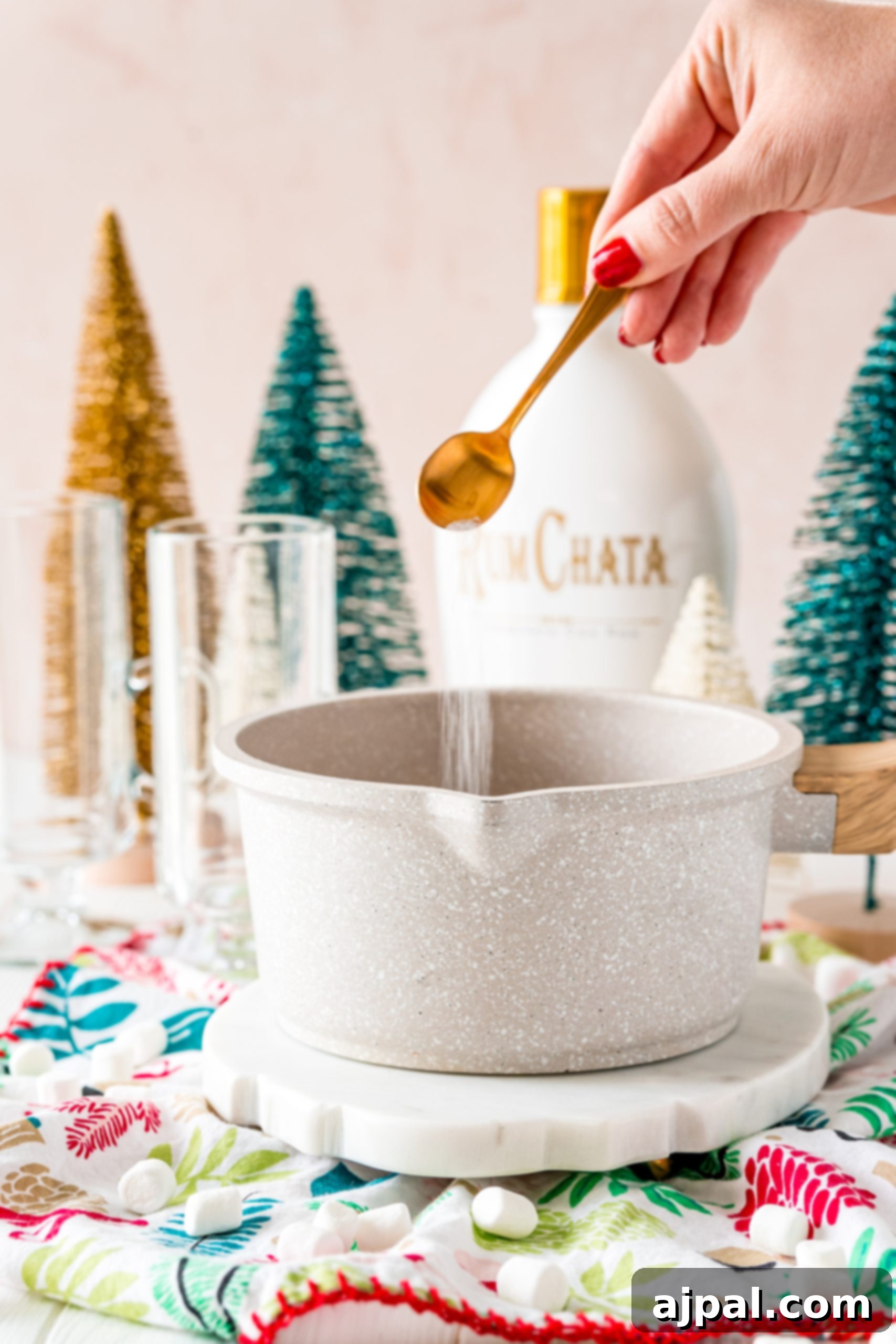 Creamy Rumchata Hot Chocolate Cocktail 8 A person is pouring rum into a bowl of boozy hot cocoa.