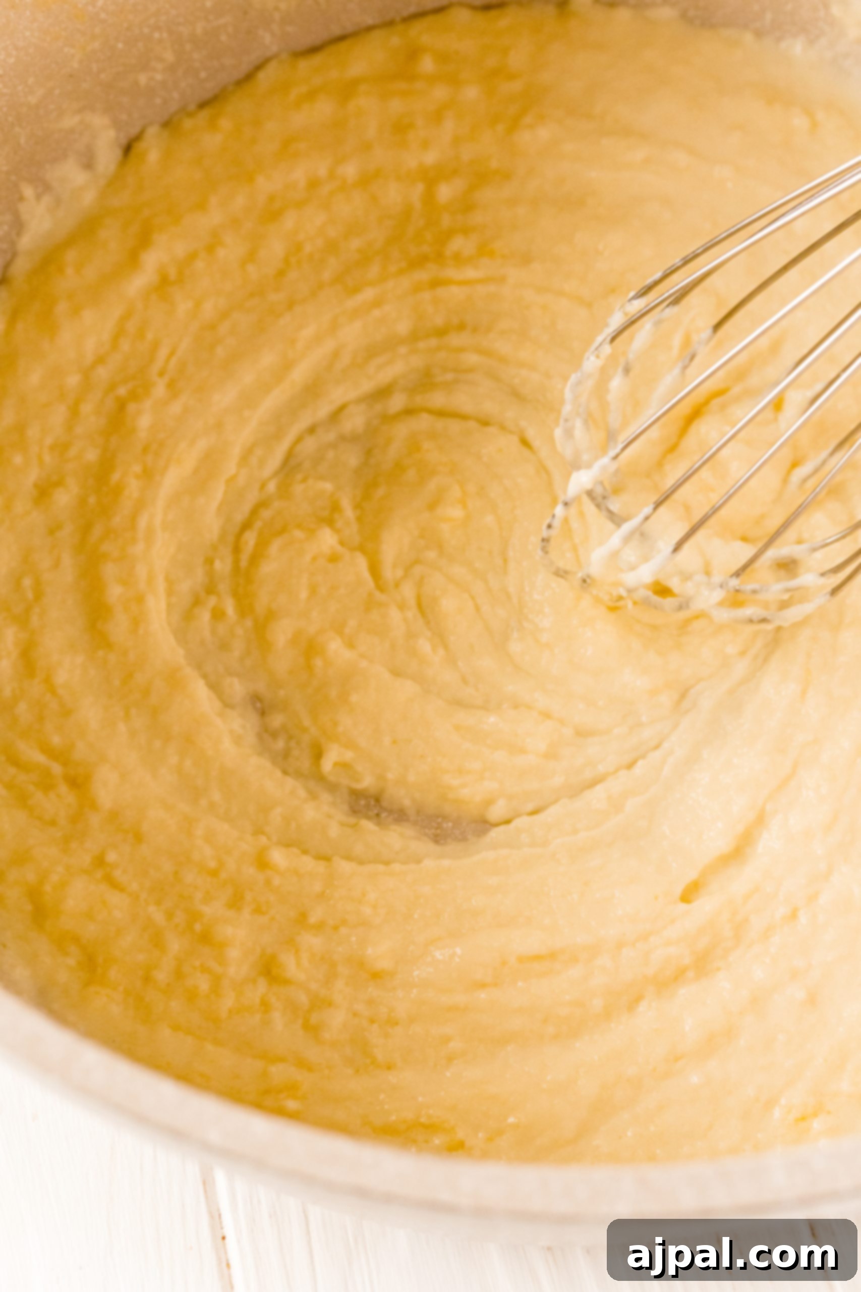 A bowl of macaroni and cheese batter with a whisk in it for an easy recipe.