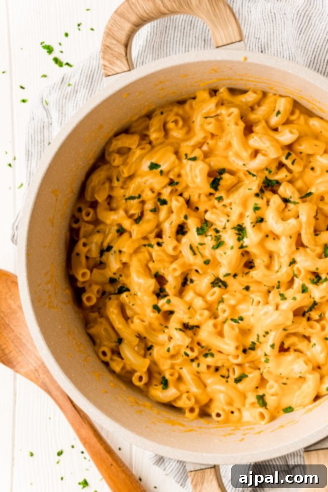 Easy macaroni and cheese recipe in a white bowl, garnished with herbs.