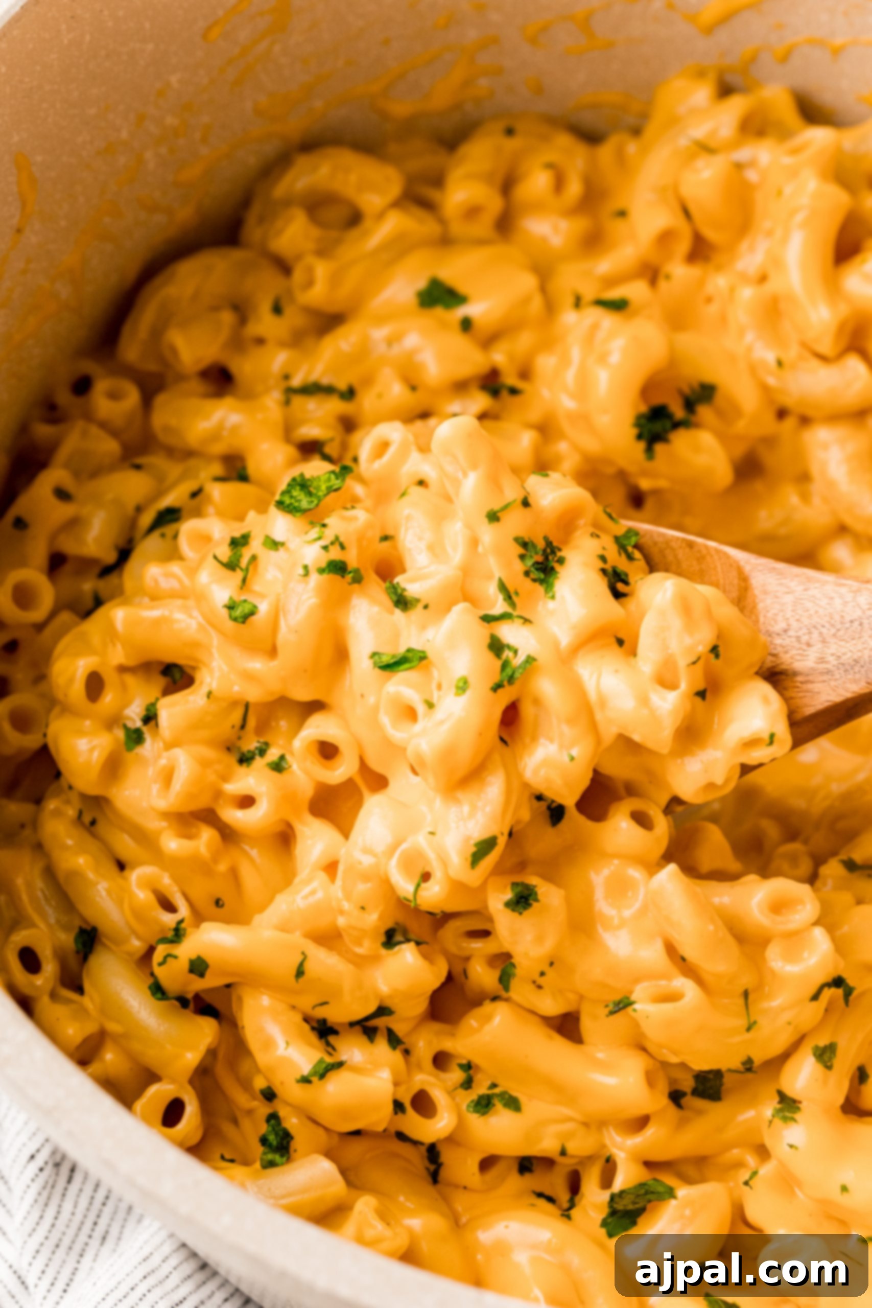 The Best Easy Mac and Cheese Recipe made in a pan with a wooden spoon.