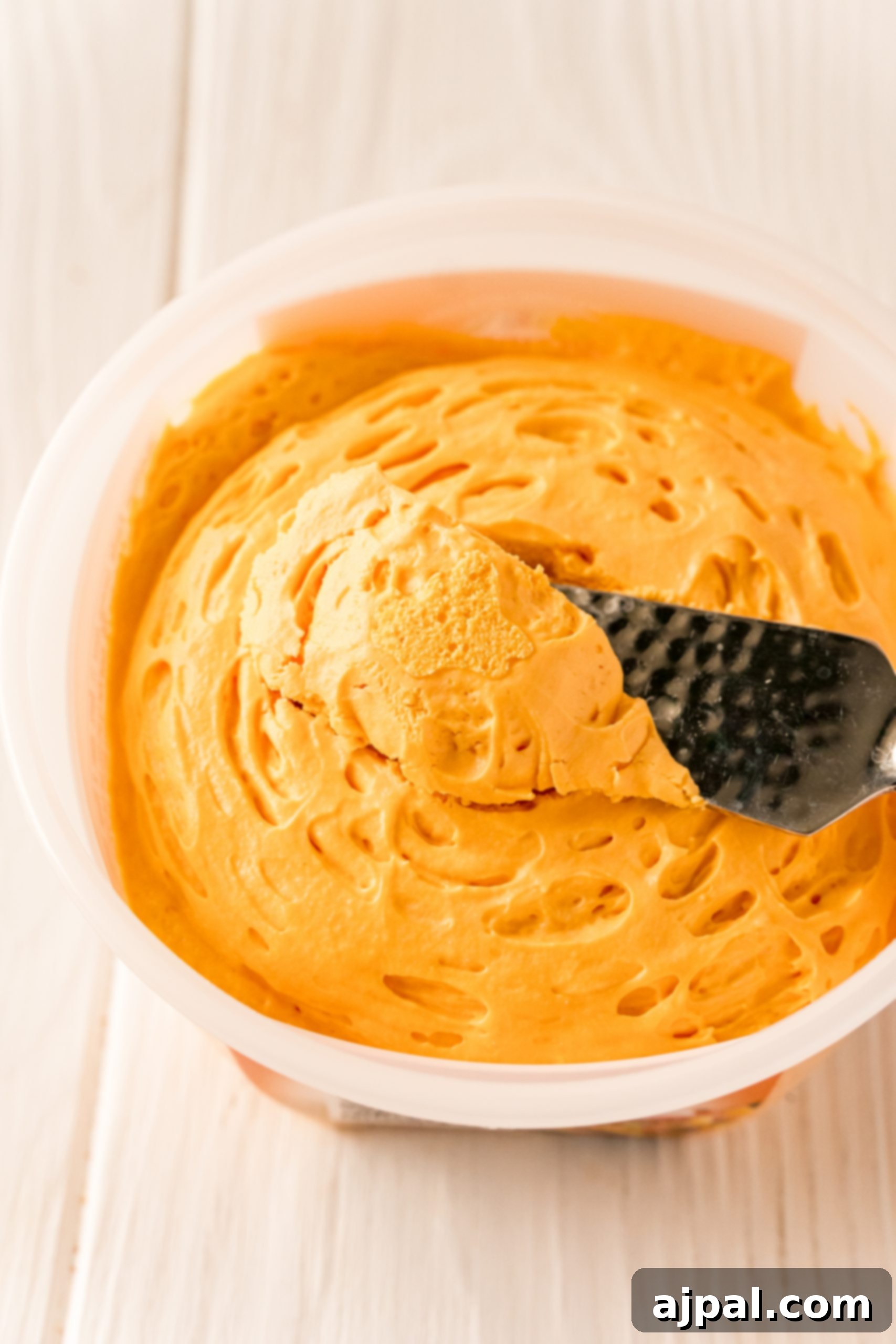 A bowl of orange icing with a spatula in it for making The Best Easy Mac and Cheese Recipe.