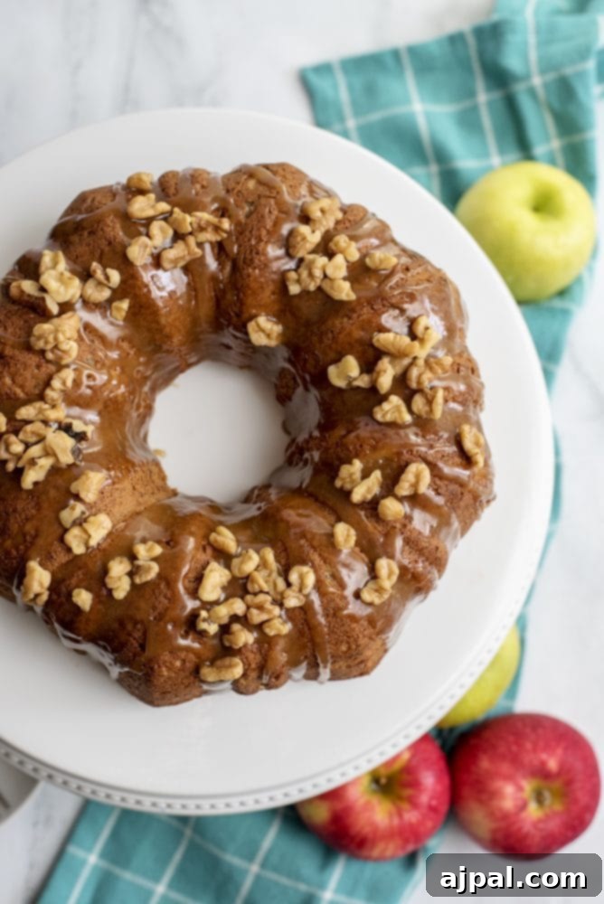 A beautifully baked brown bundt cake, generously drizzled with caramel sauce and sprinkled with chopped walnuts, ready to be served.