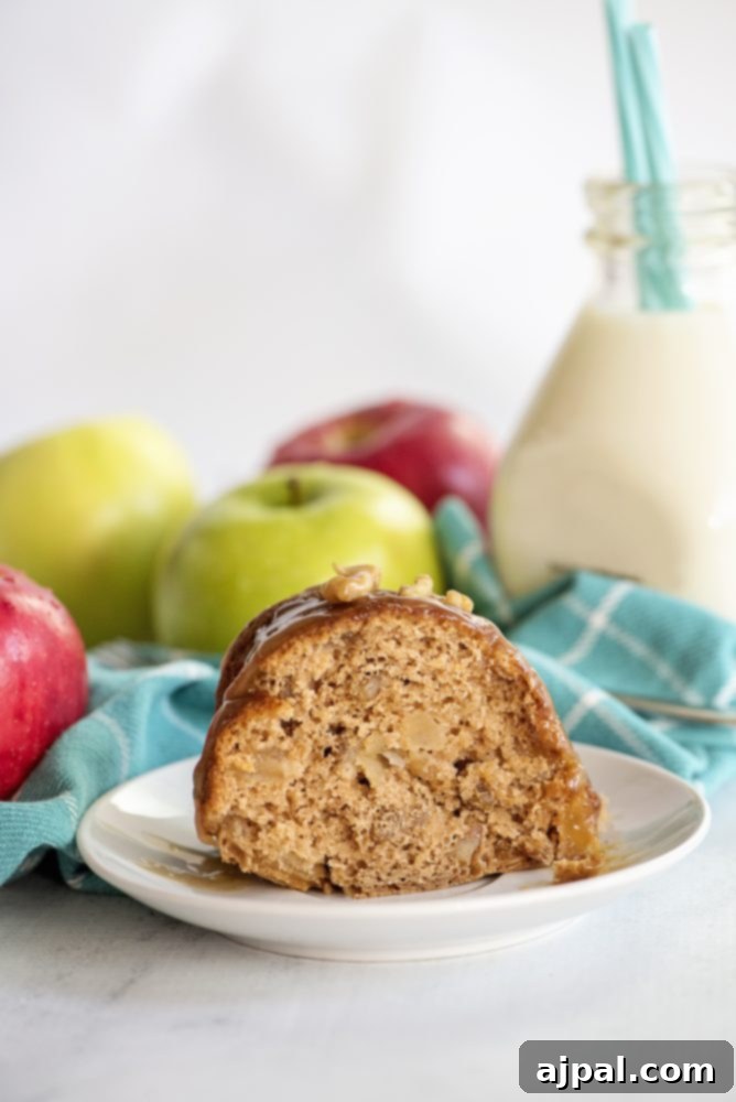 Decadent Caramel Apple Spice Cake Made Easy 3 A delicious slice of caramel apple spice bundt cake on a white plate, revealing tender apple pieces within the spiced crumb, with a glass of milk in the background.