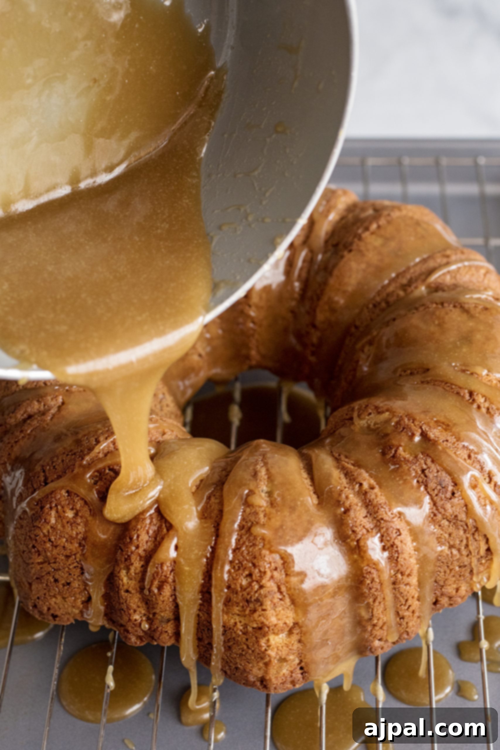 Decadent Caramel Apple Spice Cake Made Easy 9 A baked spice cake mix recipe being generously drizzled with luscious caramel sauce, enhancing its appeal.