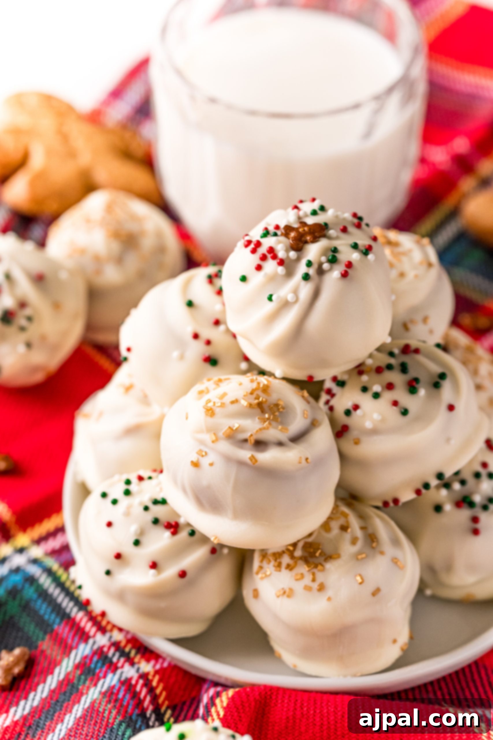 Gingerbread truffles and milk accompany Christmas cookies on a plate, creating a delightful holiday spread.