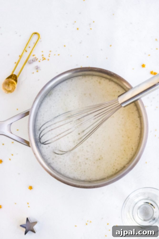 Clear jello mix dissolving in a pot with a whisk, illustrating the preparation step.