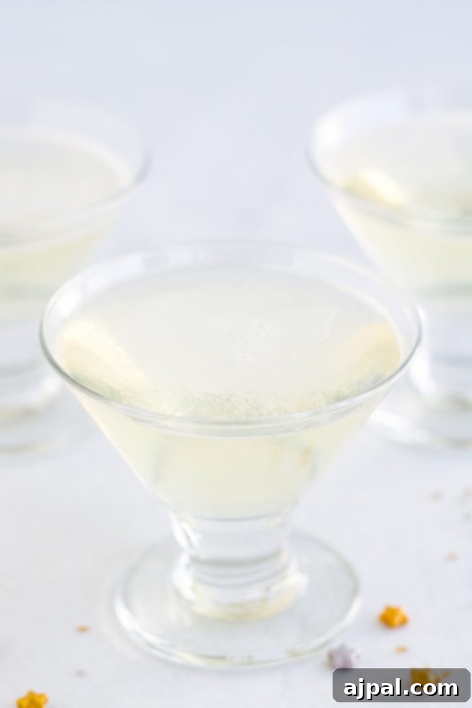 A pristine, clear champagne jello shot in a small glass, perfectly set and ready to be garnished for a party.