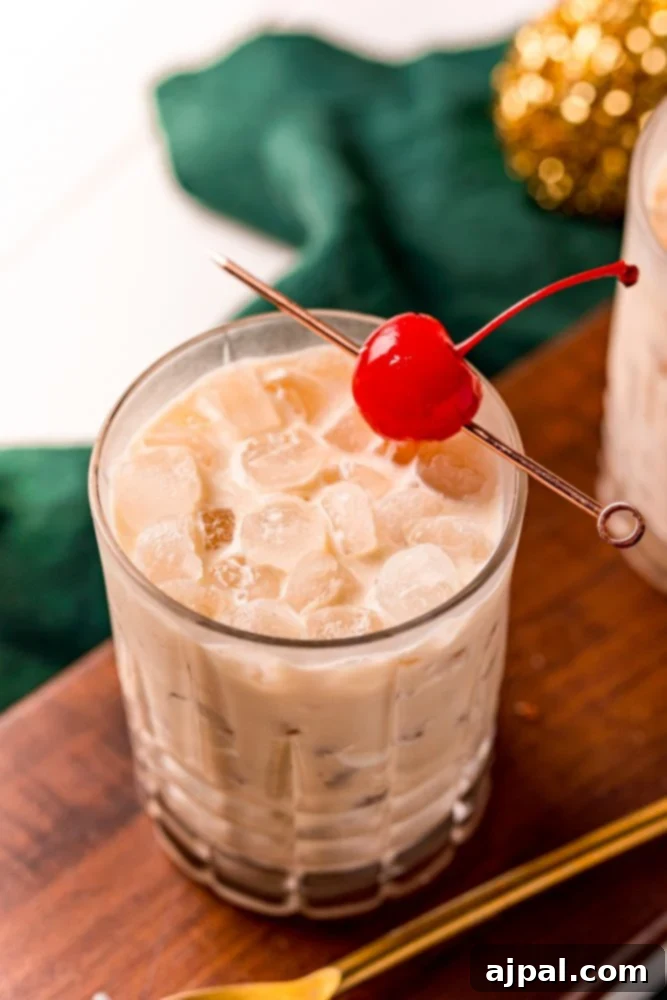 A refreshing twist on the classic White Russian cocktail, elegantly presented in a glass with a vibrant cherry garnish, showcasing the inviting Irish cream infusion.