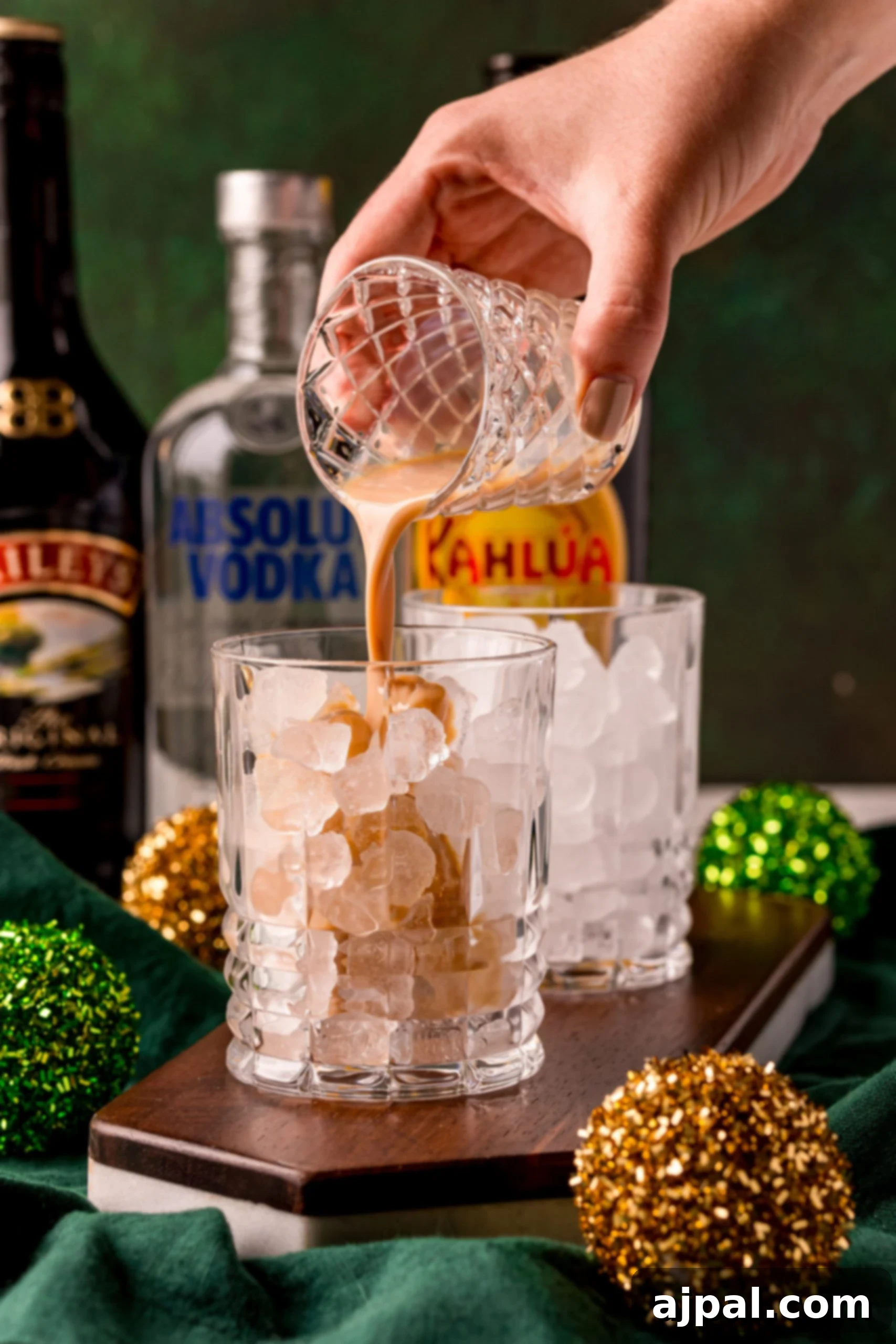 A person carefully pouring Irish Cream into a glass, starting the preparation of an Irish Cream White Russian cocktail.