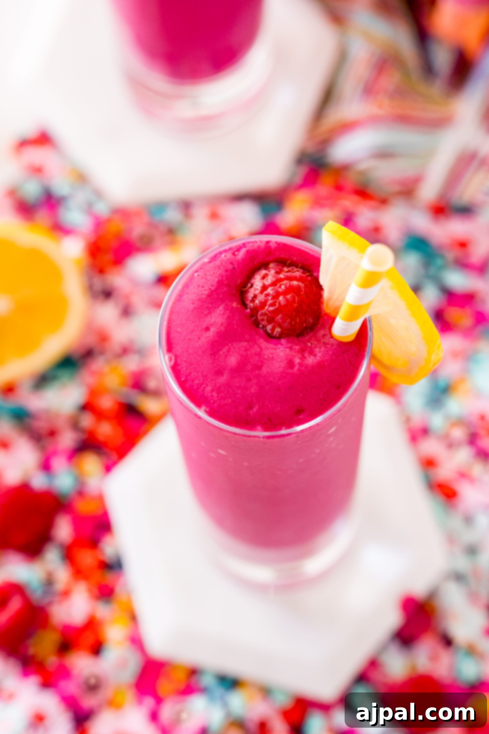 Vibrant Beet Raspberry Blend 3 A glass of raspberry beet smoothie with a slice of lemon on the rim, showcasing its vibrant color.