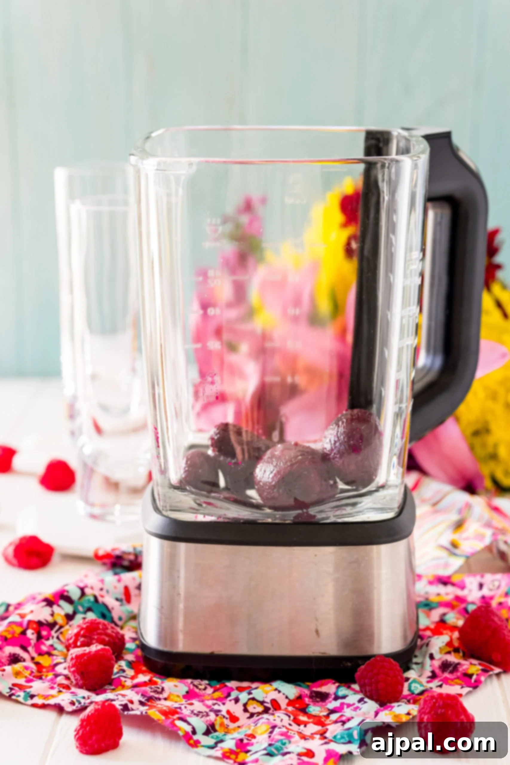 Vibrant Beet Berry Boost 8 A blender on a table filled with raspberries, ready to be blended into a Raspberry Beet Smoothie.