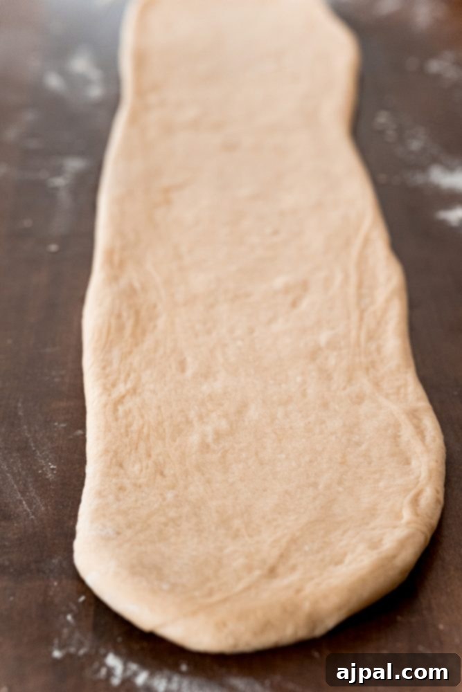 Effortless Melt-in-Your-Mouth Buttery Dinner Rolls 13 picture of roll dough flattened out onto table