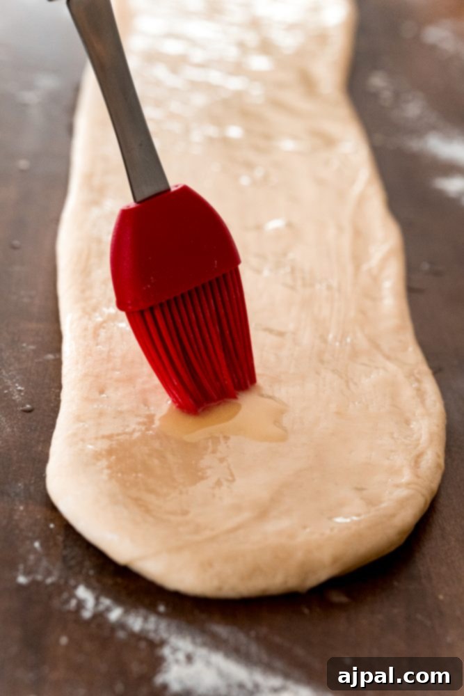 Effortless Melt-in-Your-Mouth Buttery Dinner Rolls 14 picture of silicone brush brushing butter onto bread dough