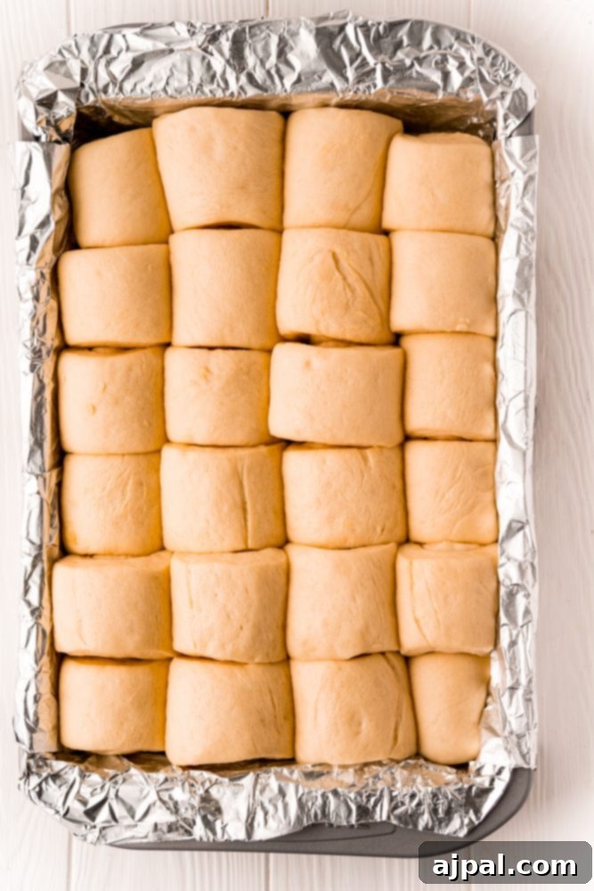 Effortless Melt-in-Your-Mouth Buttery Dinner Rolls 19 picture of risen bread rolls in baking sheet lined with foil