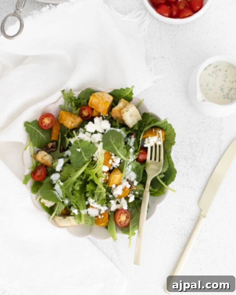 A delightful salad bowl featuring roasted sweet potato and goat cheese, presented with a fork, emphasizing its ready-to-eat appeal.