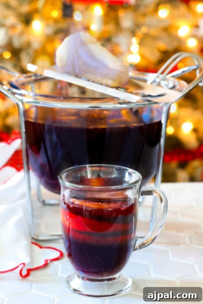 A cozy mug of Feuerzangenbowle, a flaming German rum punch, sits in front of a punch bowl with a sugar loaf on fire, evoking the festive spirit of Christmas markets.