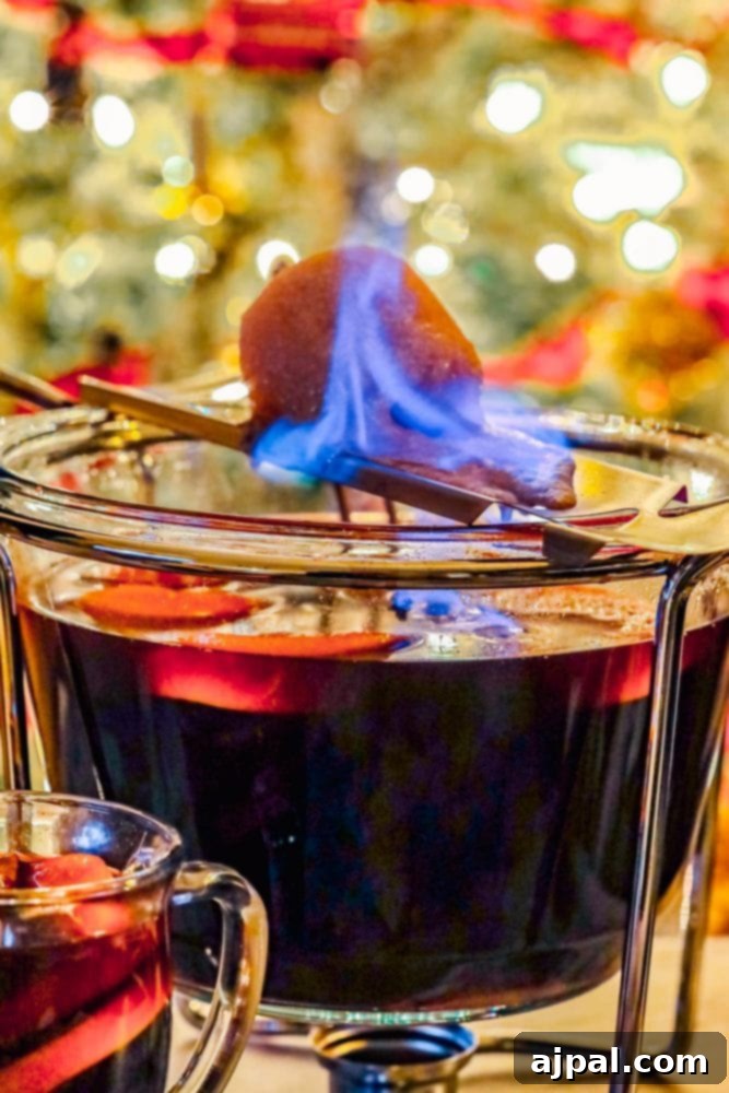 A warm mug of Feuerzangenbowle, a flaming German rum punch, positioned in front of a festive backdrop of a punch bowl and a burning sugar cone, perfect for holiday gatherings.
