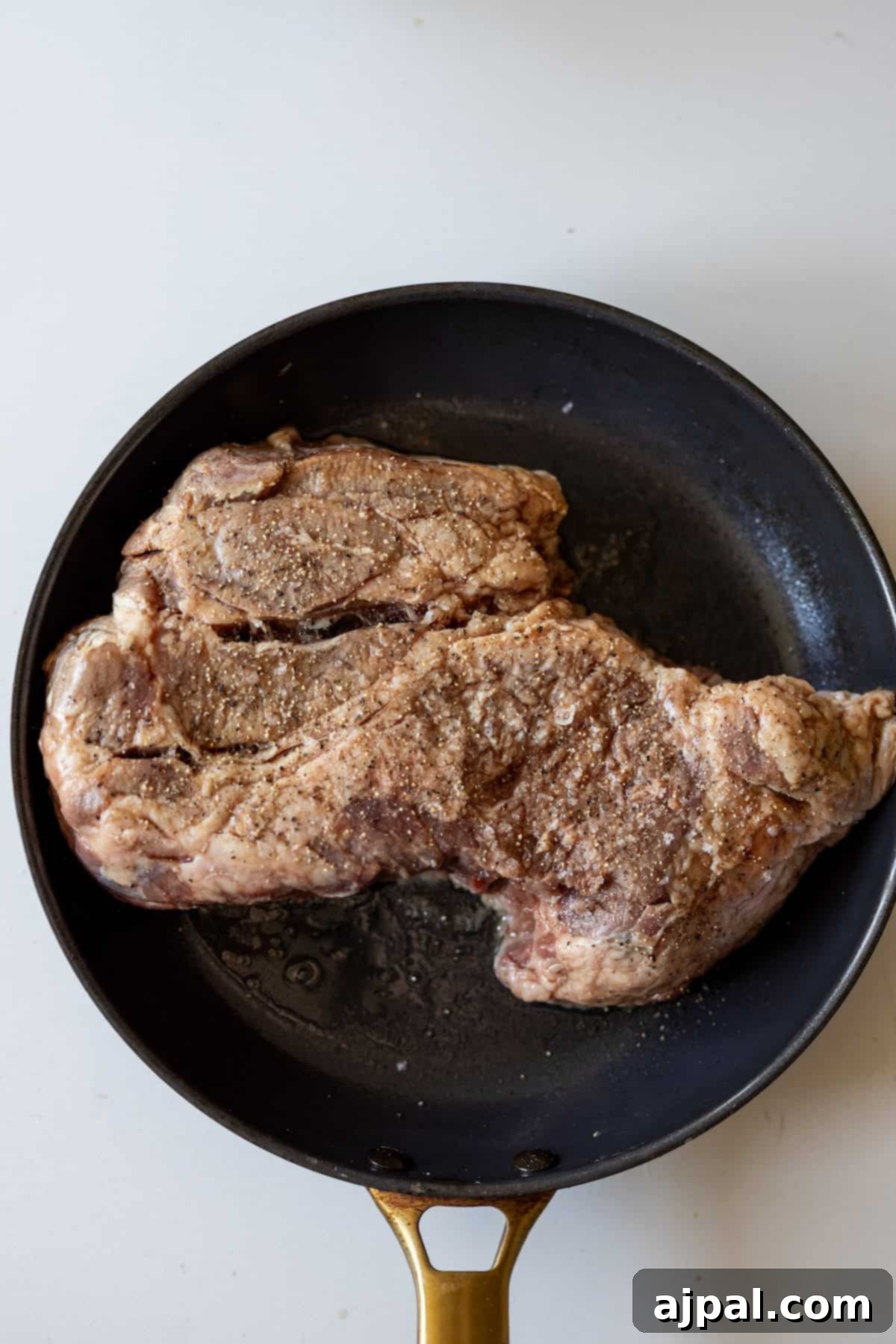 Fall-Apart Tender Instant Pot Pot Roast 4 A large, seasoned chuck roast cooking in a black Instant Pot on sauté mode, developing a beautiful brown crust.