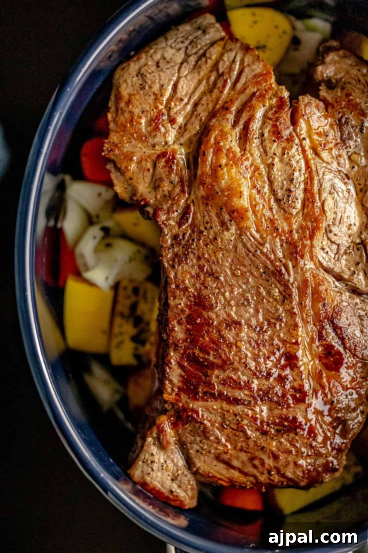 Fall-Apart Tender Instant Pot Pot Roast 6 A succulent piece of pot roast resting on a bed of sautéed onions, carrots, and potatoes, ready for pressure cooking.