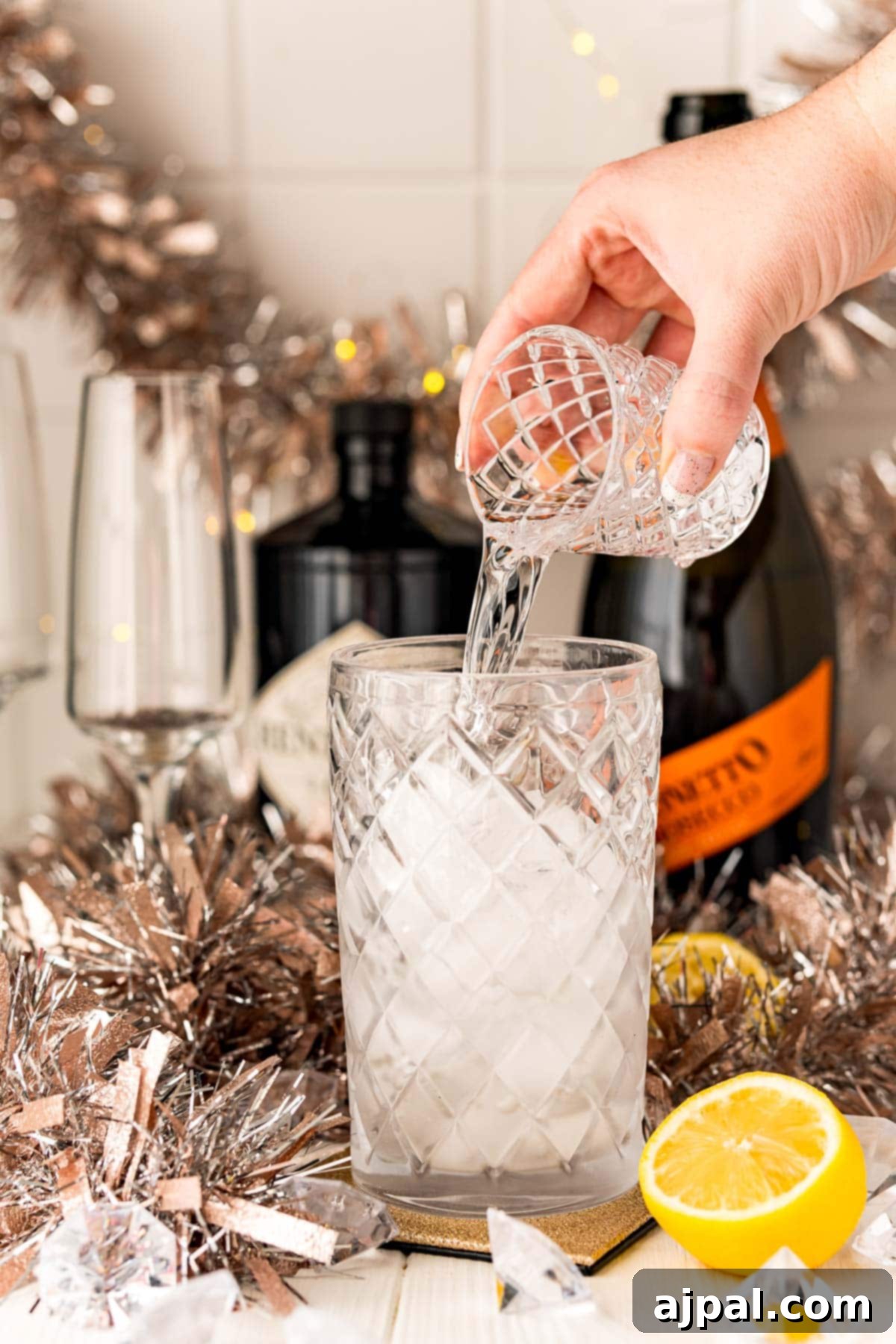 Effortless Champagne Fizz 4 A person pouring champagne into a glass creating a Champagne Gin Fizz Cocktail.