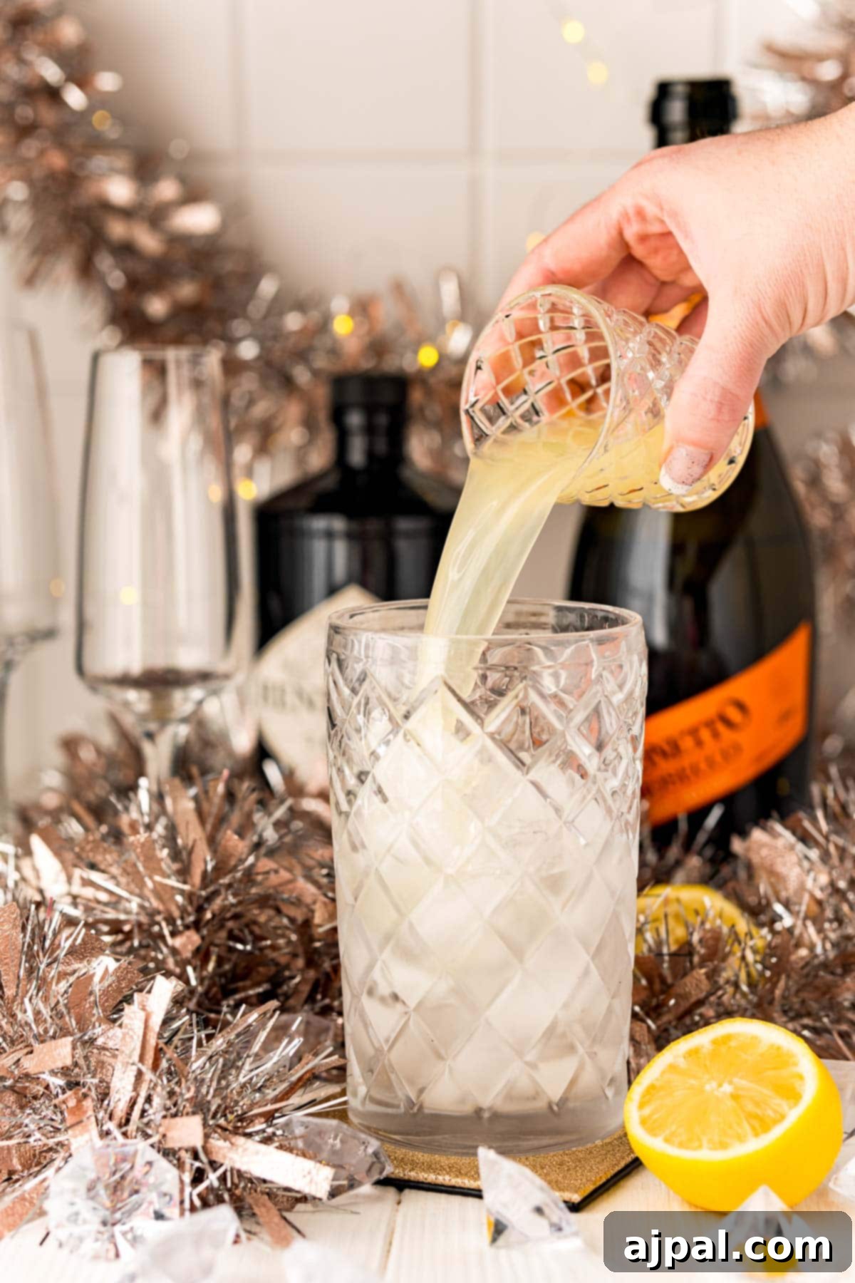 Effortless Champagne Fizz 5 A person pouring a Champagne gin cocktail into a glass.