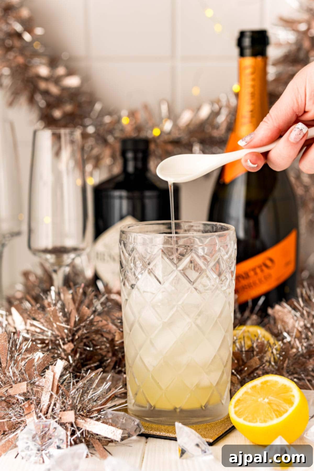 Effortless Champagne Fizz 6 A person is squeezing a lemon into a glass of champagne.