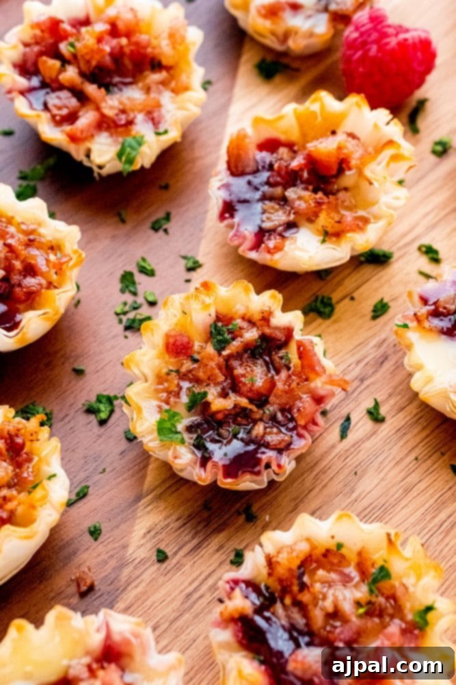 Cheesy Bacon Raspberry Morsels 2 Delicate phyllo cups filled with creamy cheese, vibrant raspberry jam, and crispy bacon bits, ready to be served.