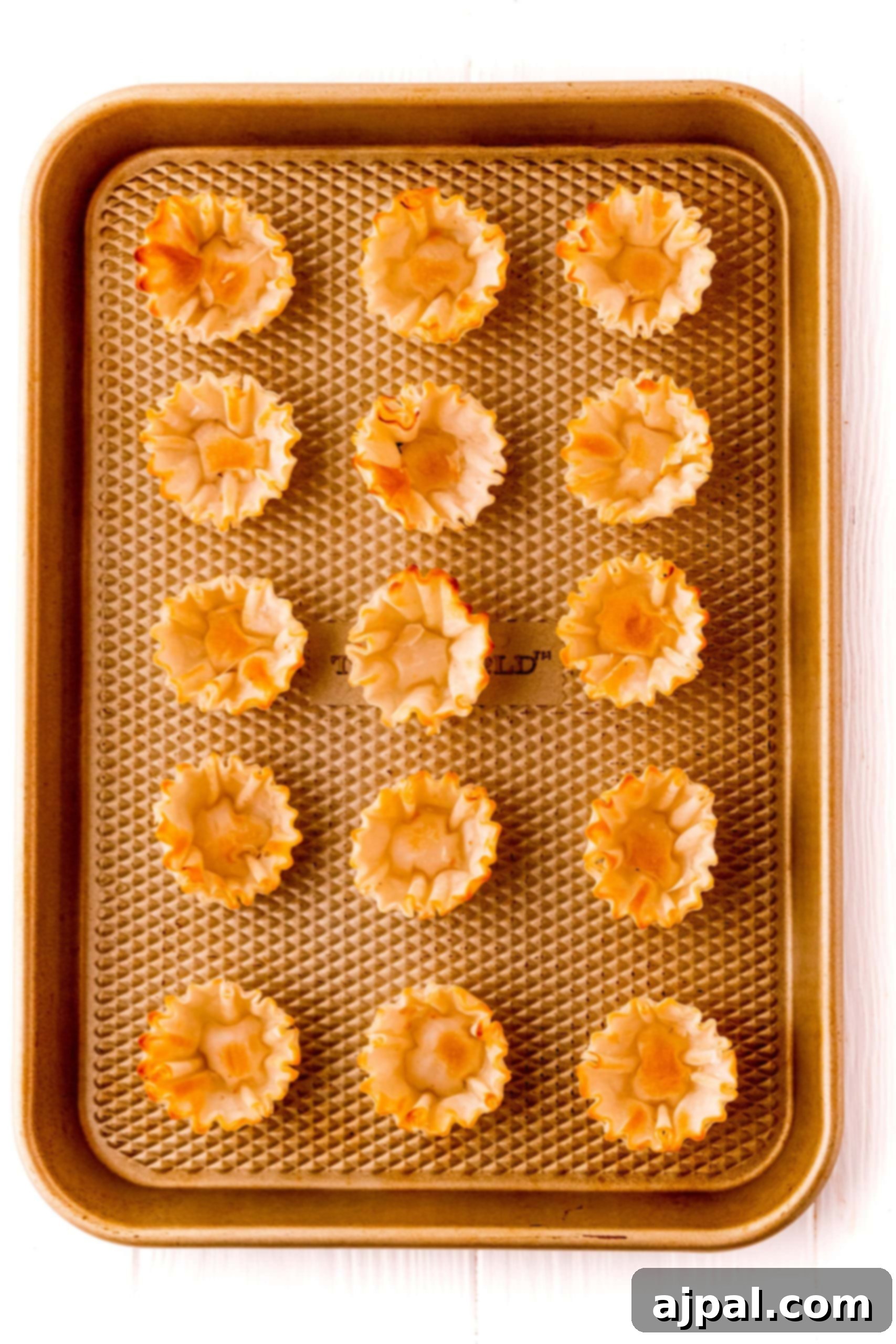Cheesy Bacon Raspberry Morsels 8 A pristine baking sheet neatly filled with mini raspberry tarts, ready for baking on a clean white background.