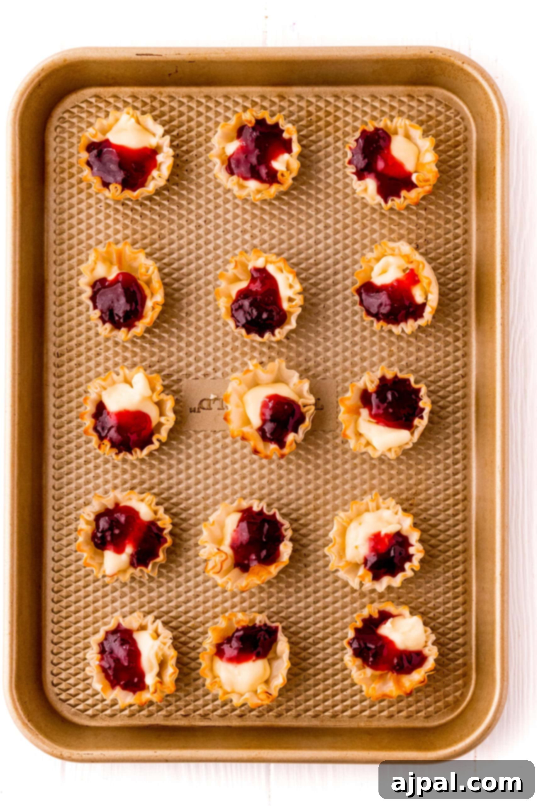 Cheesy Bacon Raspberry Morsels 10 A pristine tray of mini tarts, each adorned with a dollop of vibrant cranberry sauce, offering a delightful visual treat.