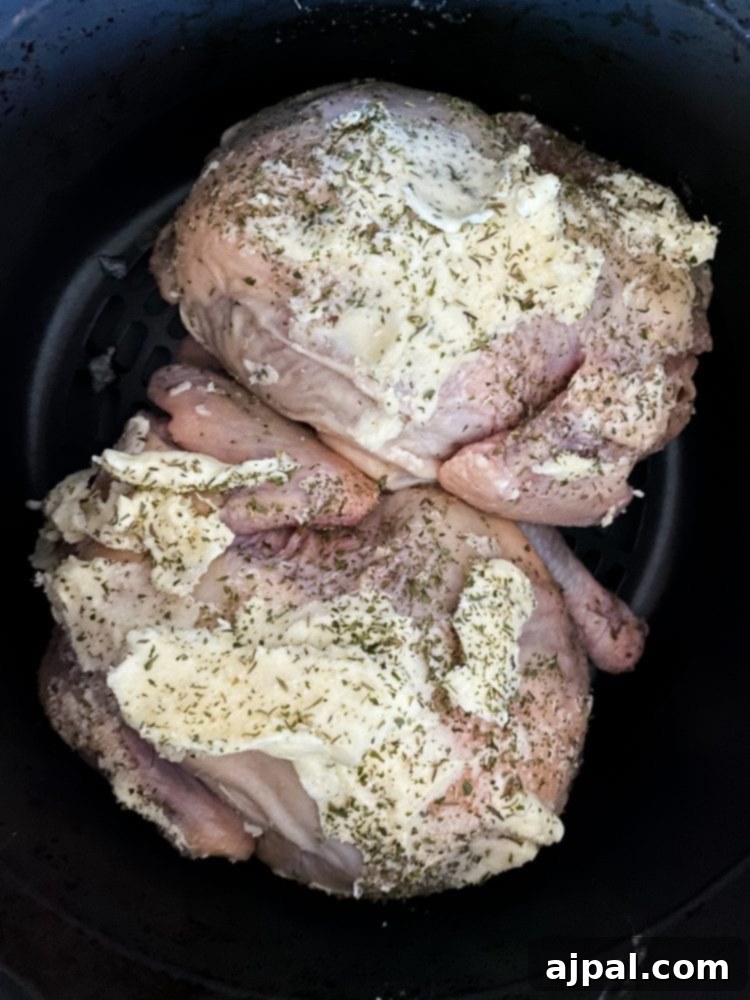 Golden Crispy Air Fryer Cornish Hen 8 Seasoned raw Cornish game hens carefully arranged in an air fryer basket, along with butter and herbs.