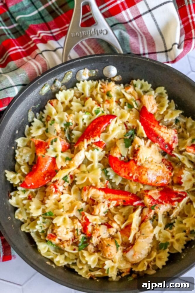 Delicious bowtie pasta in a skillet with herbs, cheese, and succulent lobster meat, ready to be served.