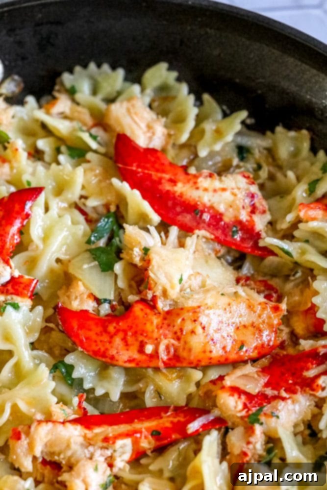 Effortless Lobster Pasta Delight 4 bowtie pasta in a pan with herbs, cheese, and lobster meat