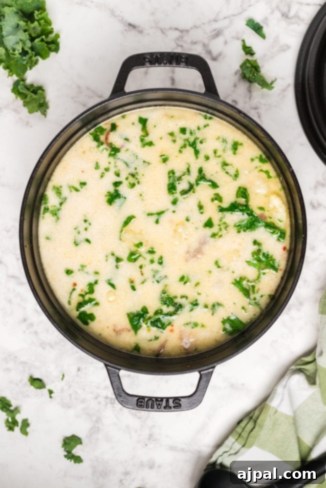 Simple Creamy Keto Tuscan Kale Soup 3 A beautifully garnished bowl of Keto Zuppa Toscana, featuring hearty sausage, vibrant kale, and a creamy broth, on a marble table.