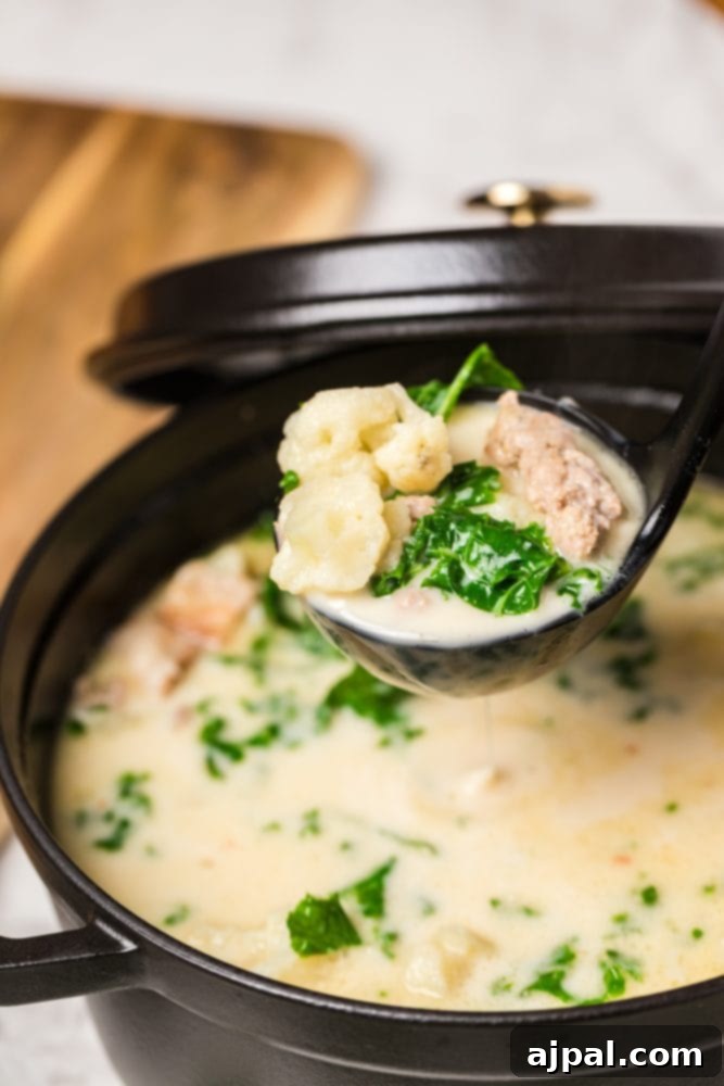 Simple Creamy Keto Tuscan Kale Soup 7 A spoonful of Keto Tuscan Kale Soup, showcasing the creamy broth, pieces of sausage, and tender kale, lifted from a full bowl.