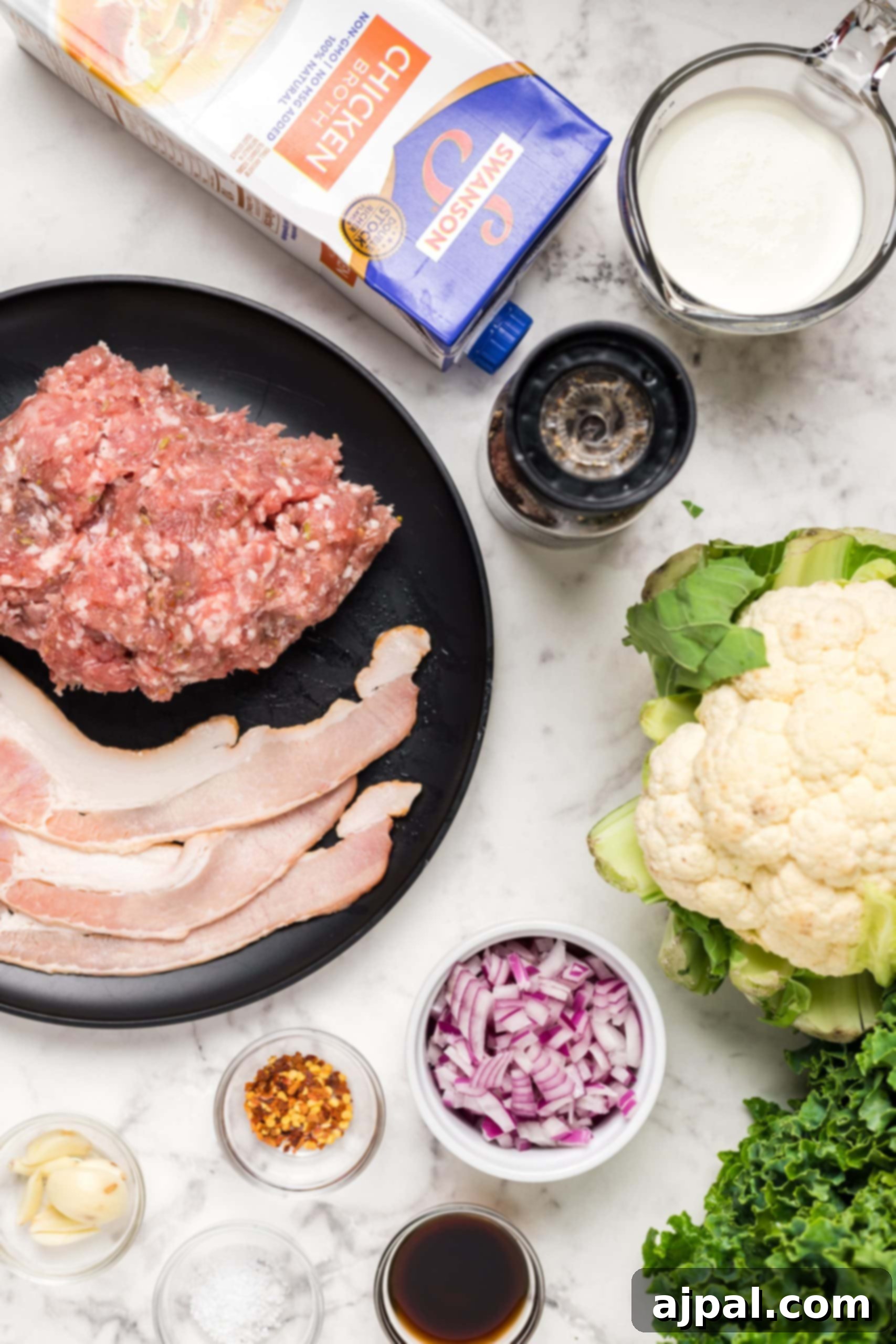 Simple Creamy Keto Tuscan Kale Soup 9 Ingredients for Easy Keto Tuscan Kale Soup, including meatballs, sausage, and vegetables, laid out on a kitchen counter.