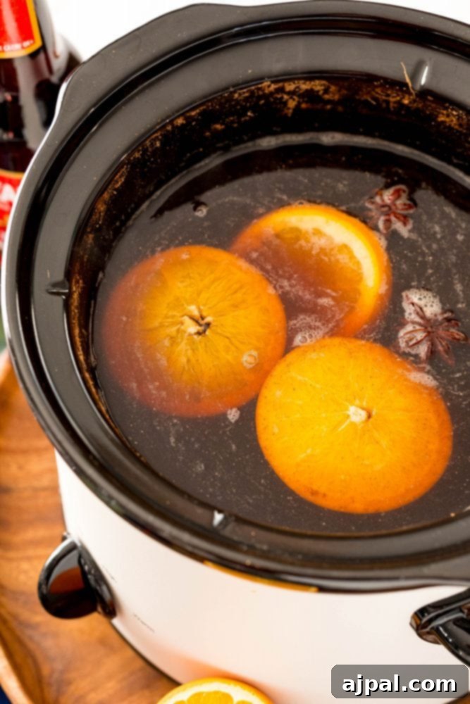 picture of slow cooker with oranges floating in it 