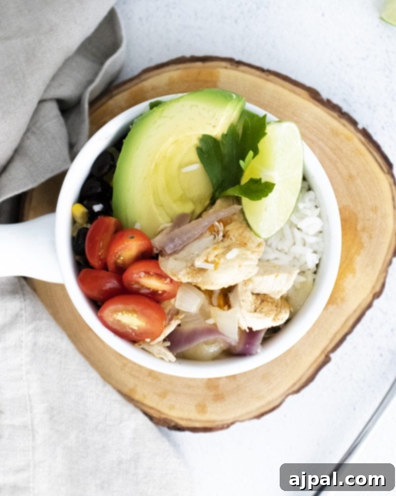 A vibrant Instant Pot Chicken Fajita Bowl featuring succulent chicken, sliced avocados, fresh tomatoes, fluffy rice, and a zesty lime wedge, beautifully arranged on a rustic wooden table.