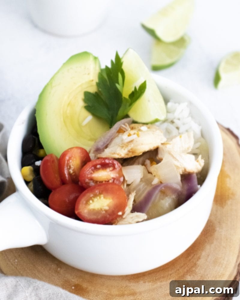 A beautifully presented keto chicken fajita bowl, featuring tender chicken, fluffy cauliflower rice, ripe avocado slices, and vibrant cherry tomatoes, on a clean white background.