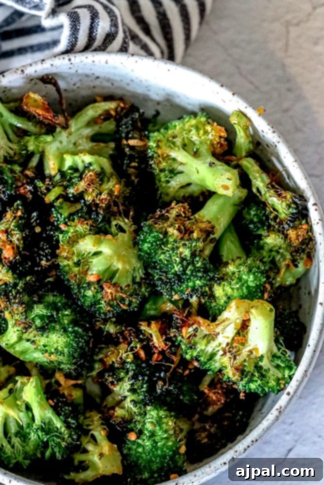 Crispy Air Fried Broccoli 5 A bowl of hot, crispy air fryer broccoli served, garnished with fresh herbs, against a soft background.