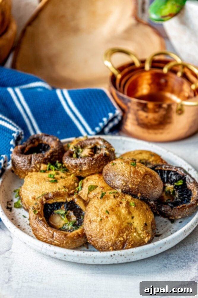 A close-up of air-fried mushrooms served as a delicious side dish on a white plate, next to a small bowl.