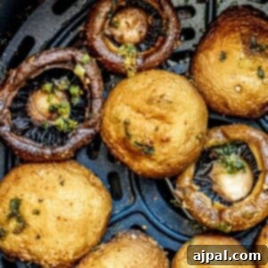 A visual of perfectly air-fried mushrooms resting in an air fryer basket, showing their cooked and delicious texture.