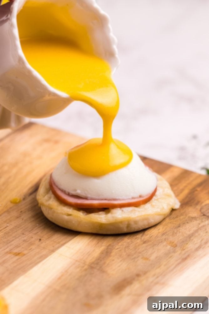 Pouring rich hollandaise sauce over a prepared Eggs Benedict, featuring an English muffin, Canadian bacon, and a poached egg.